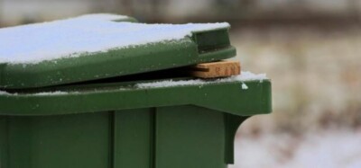 Foto van groene container met sneeuwlaagje en houtje onder deksel om vastvriezen te voorkomen