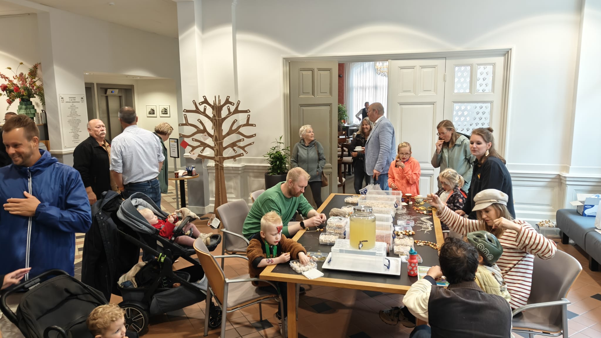 Op de foto staan ouders en kinderen die knutselen aan een tafel in de hal van het gemeentehuis
