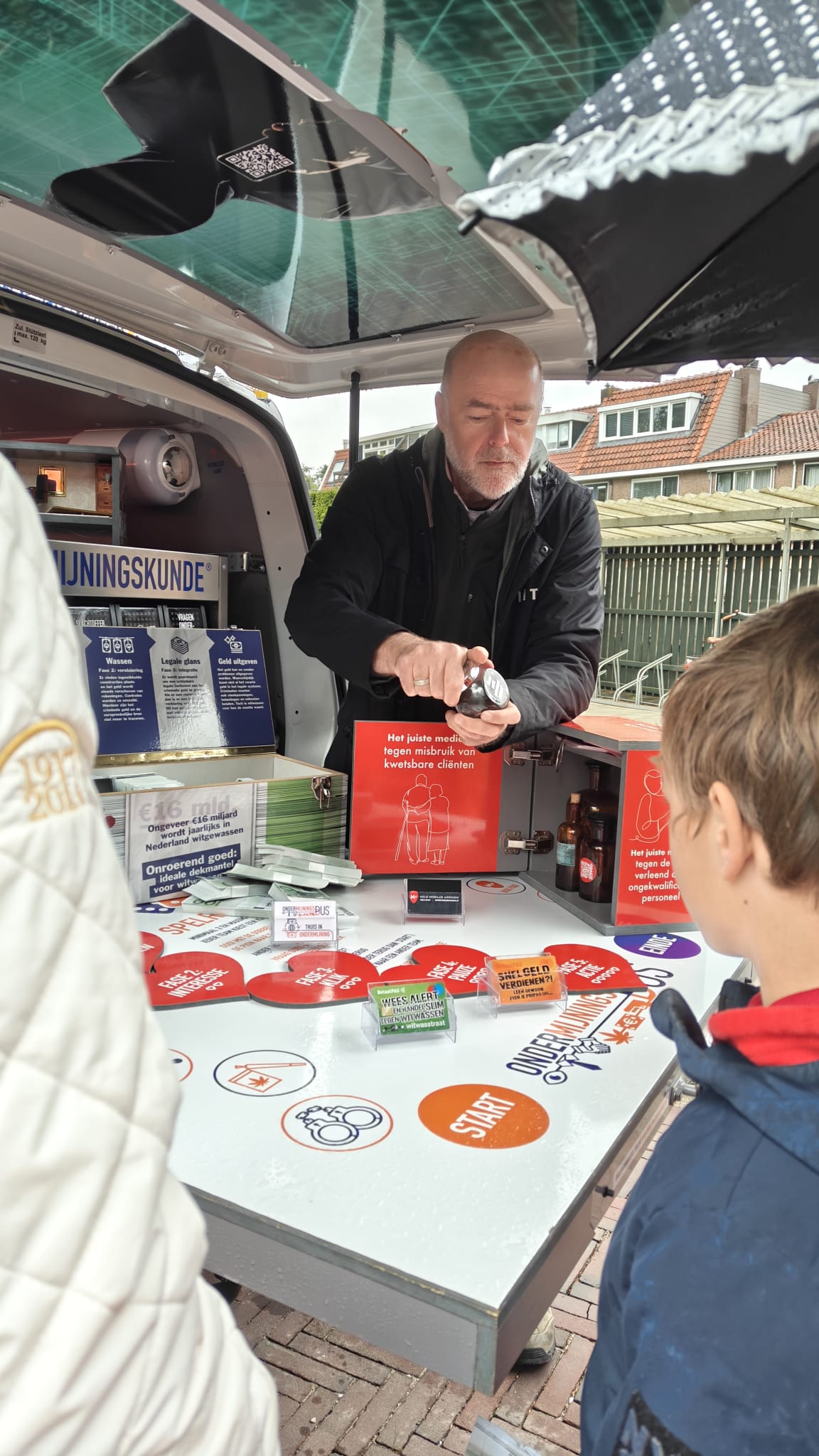 Op de foto staat een medewerker van de ondermijningsbus die uitleg geeft aan een jongen
