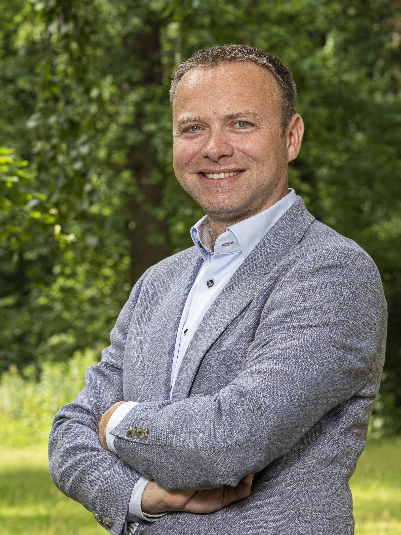 Jeffrey versluis kijkt met gekruiste armen lachend in de camera.