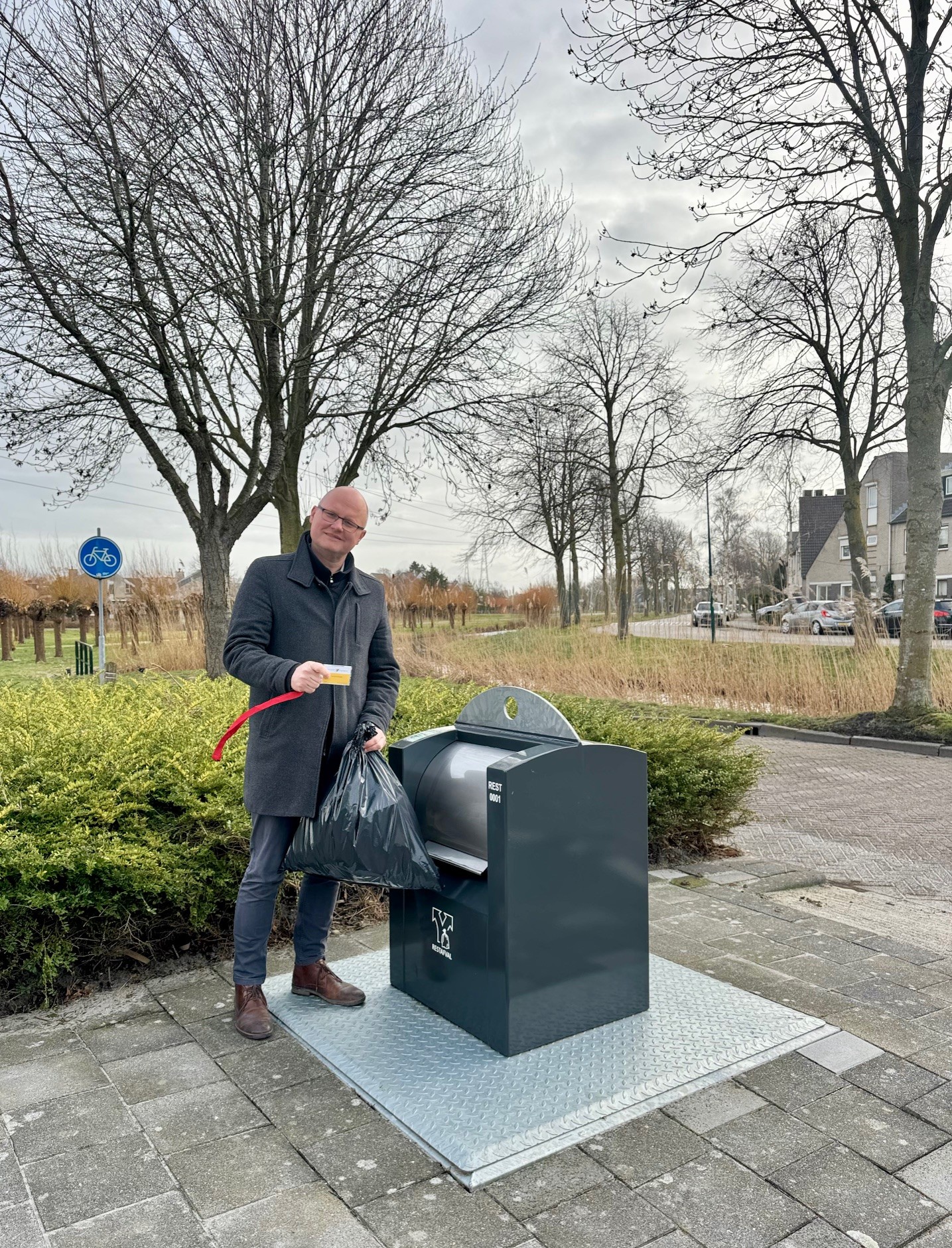 Wethouder Elfred Bus opent een ondergrondse container met een containerpas