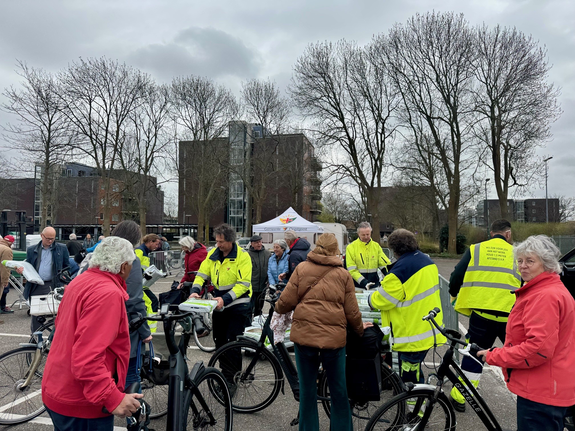 Inwoners halen met hun fiets gratis compost op. Wethouder Elfred Bus helpt mee met uitdelen.