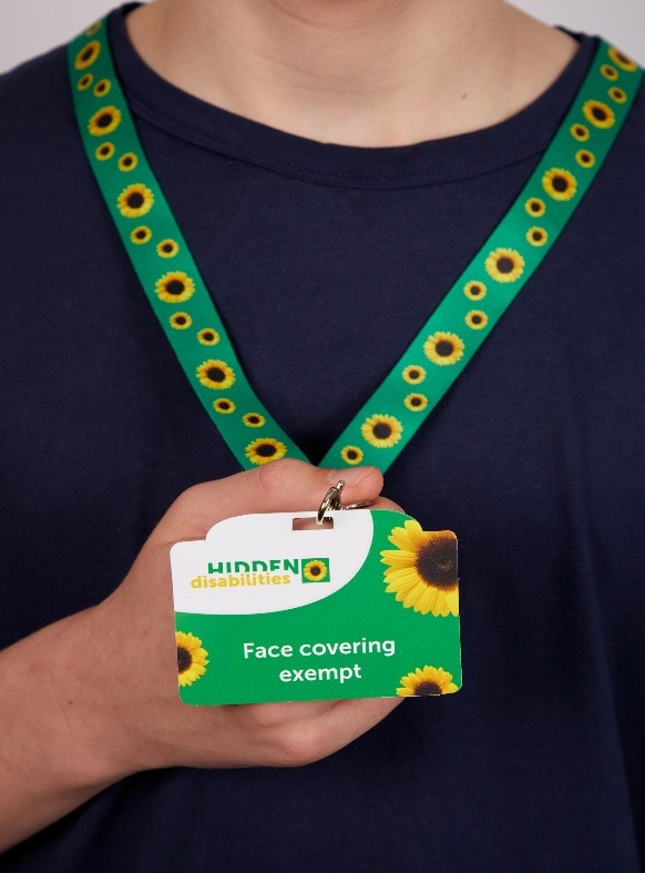 Een persoon draagt een groen sleutelkoord met afbeeldingen van zonnebloemen