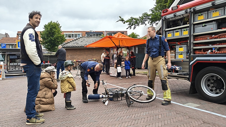 Op de foto ziet u een gezin dat kijkt bij een brandweerman voor een brandweerauto