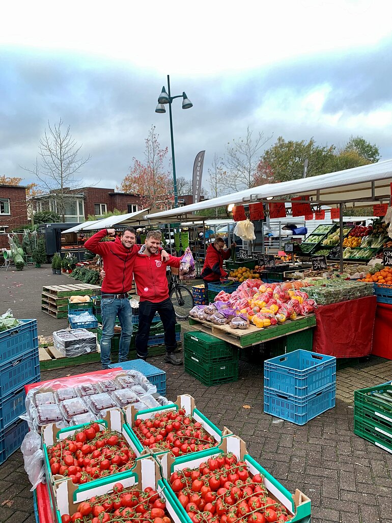 Foto van marktmedewerkers achter groentenkraam