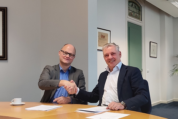 foto van wethouder elfred bus en peter van den hul, directeur bij van der valk die elkaar de hand schudden