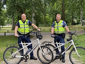Afbeelding van de gemeentelijke opsporingsambetaneren bij hun fiets